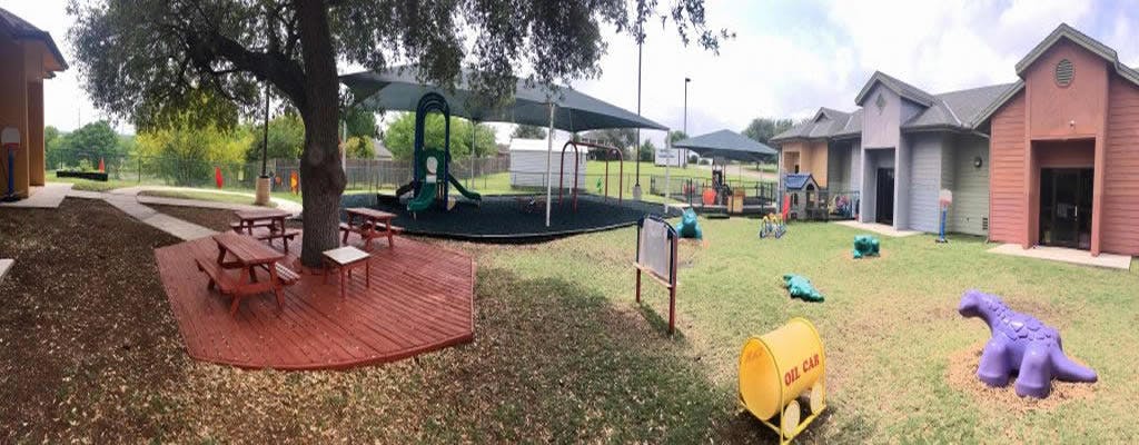 Outdoor playground with picnic tables, slides, and small buildings