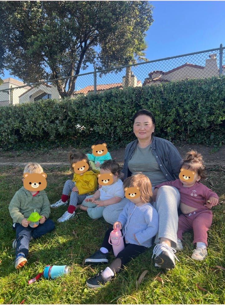 Adult person sitting on grass with five children