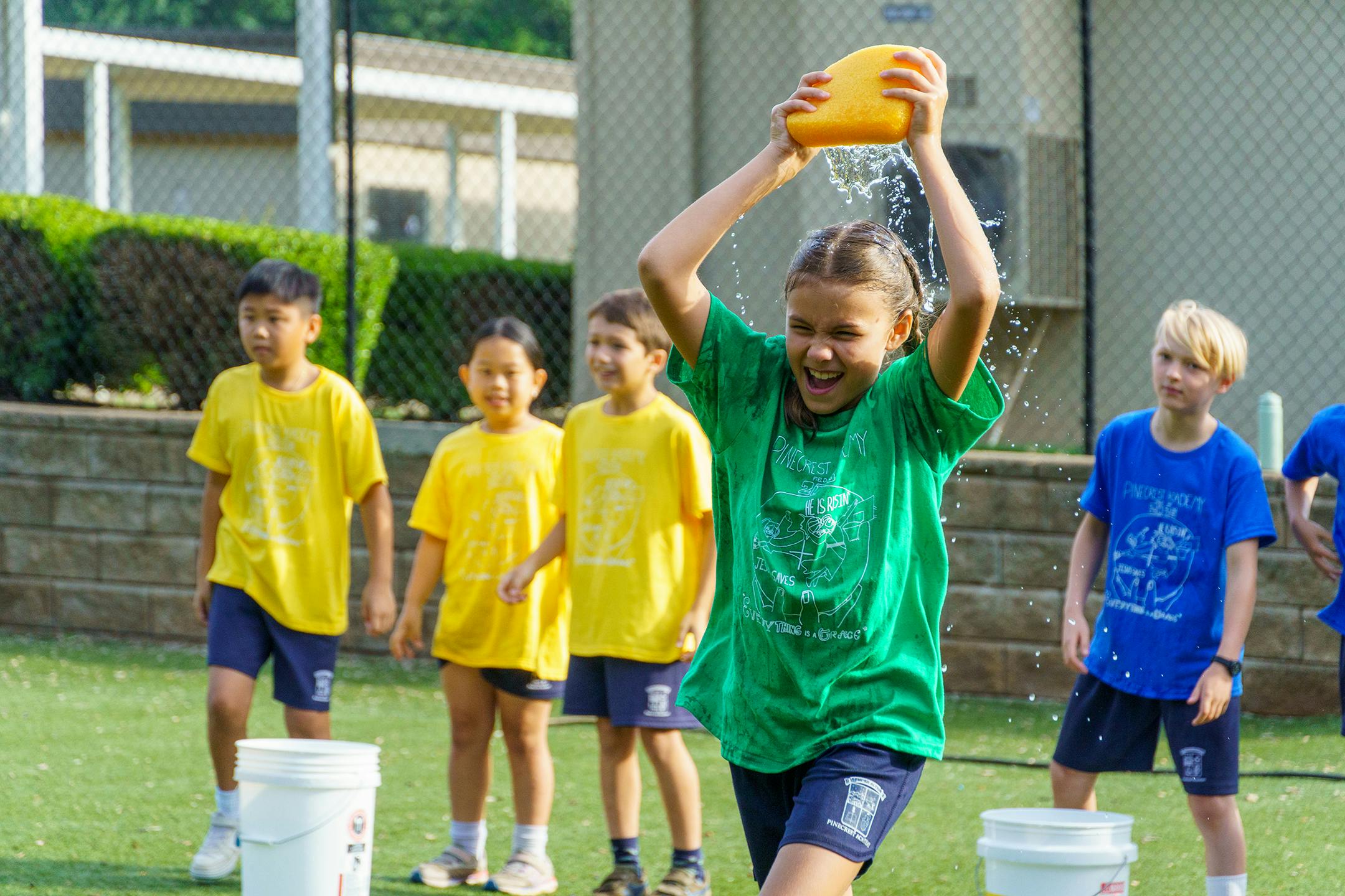 Child pouring water over their head from a yellow bucket