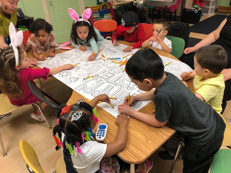 Children coloring a large paper on a table
