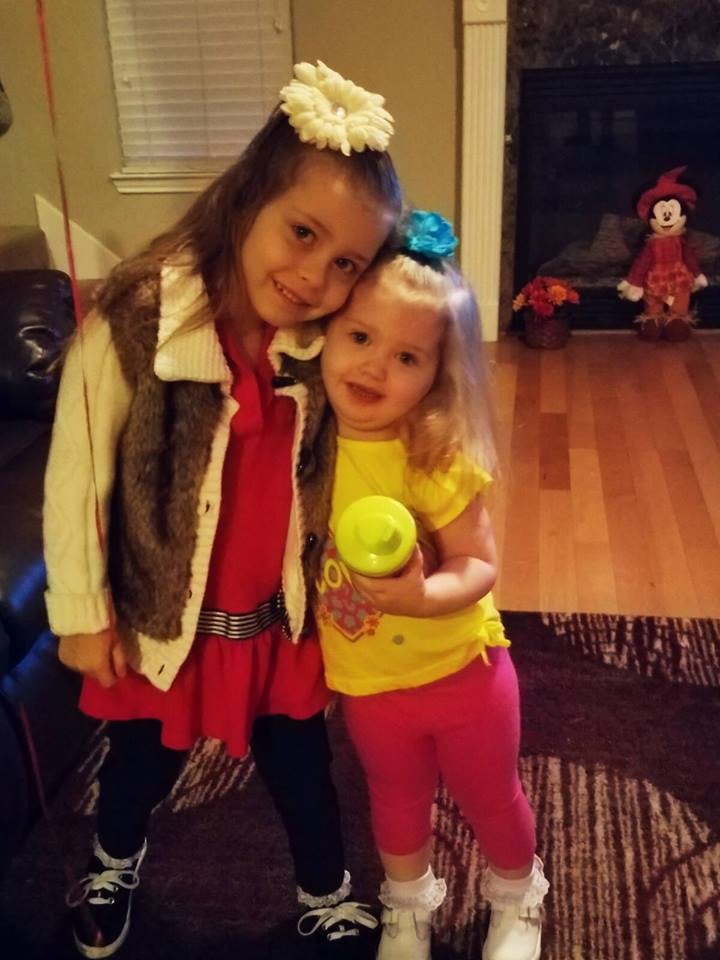 Two children standing together, one holding a yellow cup