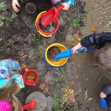 Children playing in mud with buckets and shovels