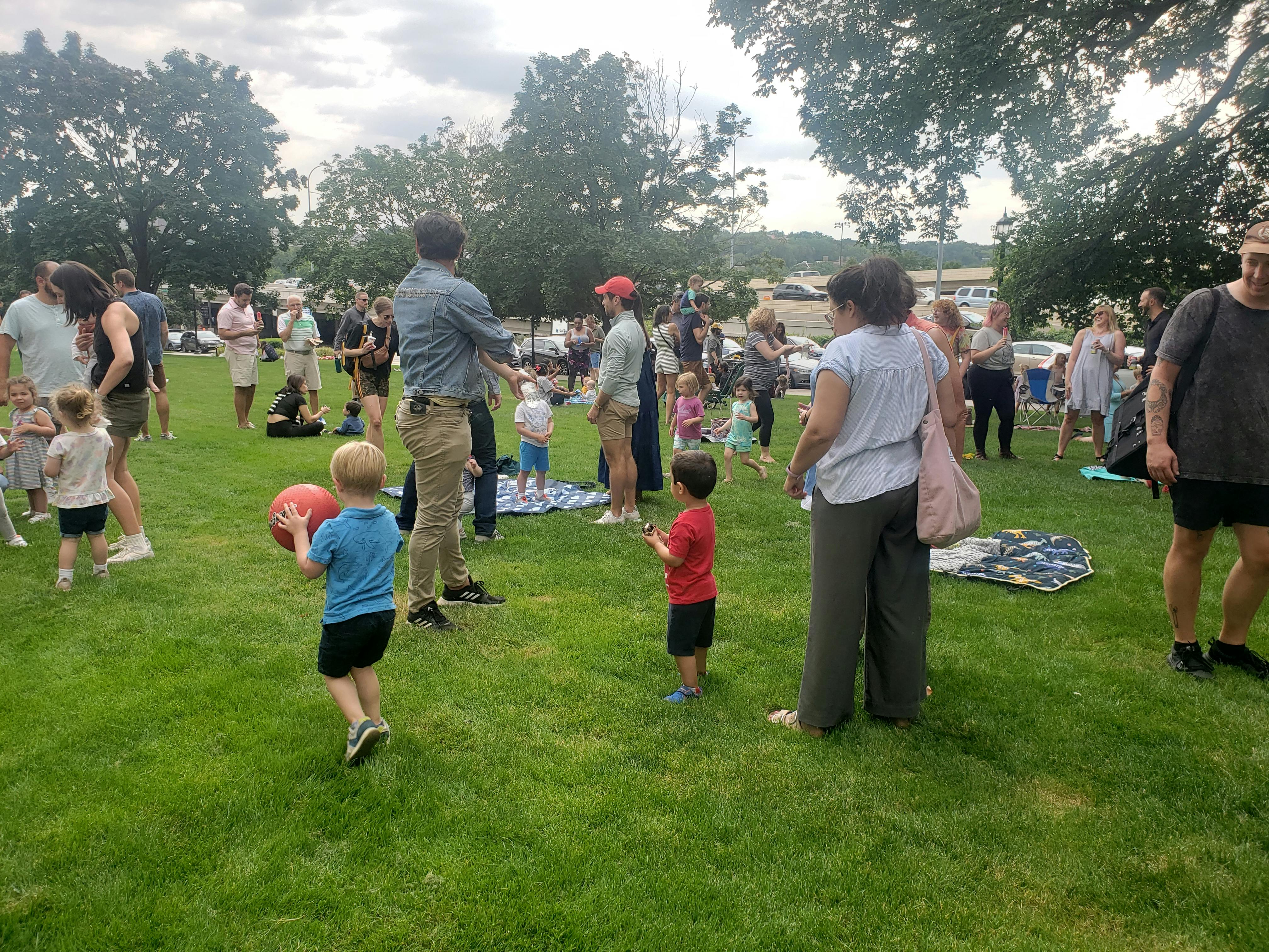 Group of people and children gathered on a park lawn