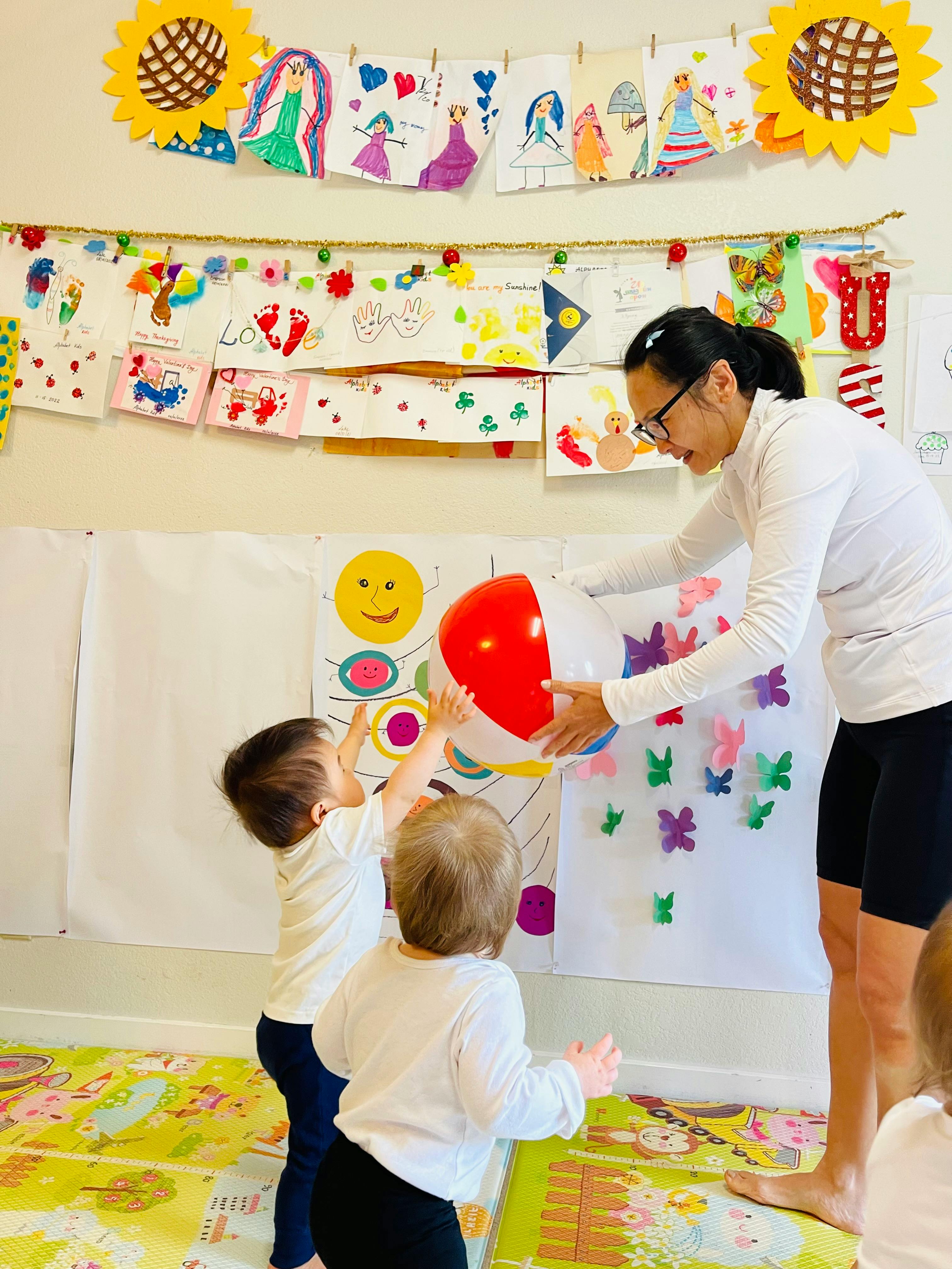 Person holding a beach ball for two children