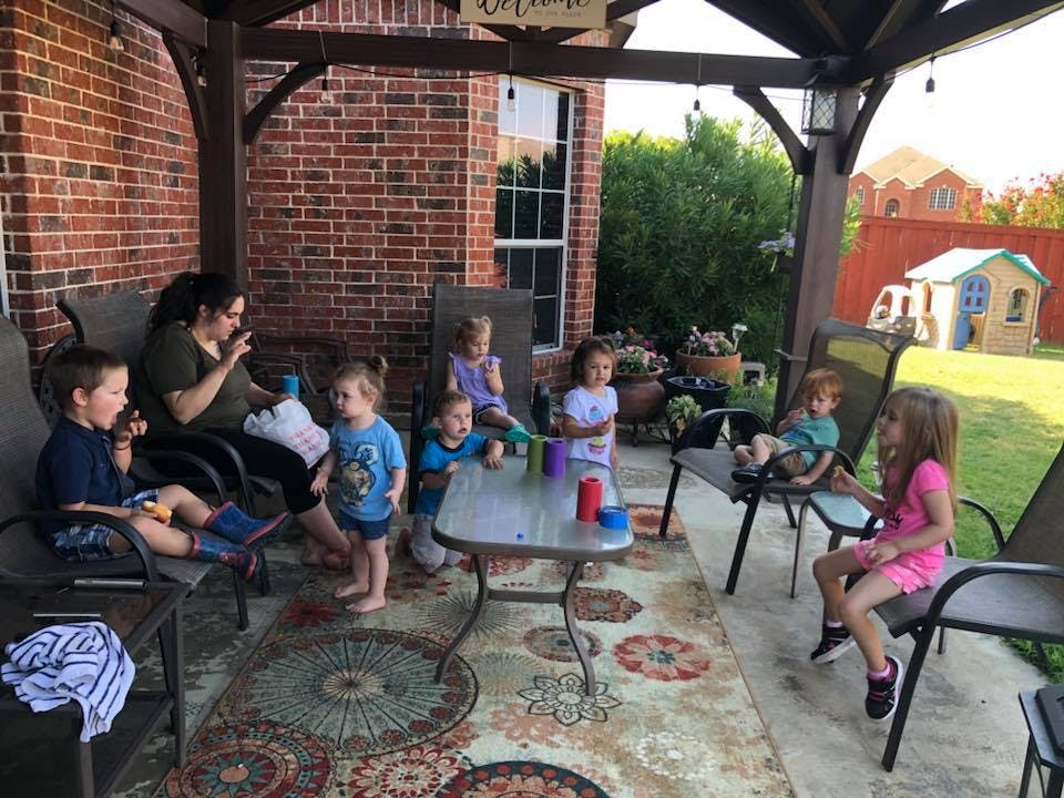 Adult and multiple children gathered on a patio