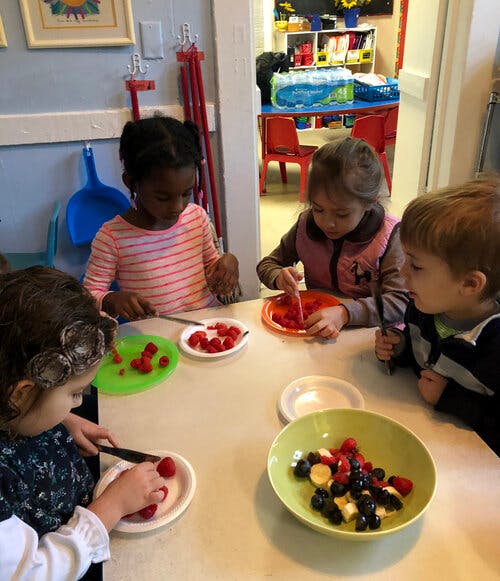 Children preparing fruit at a table