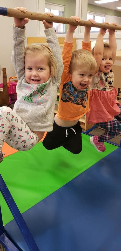 Three children hanging from a bar