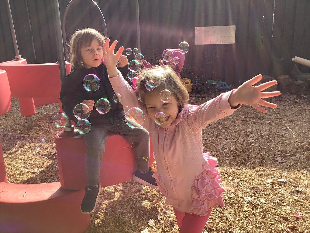 Two children playing with bubbles outdoors
