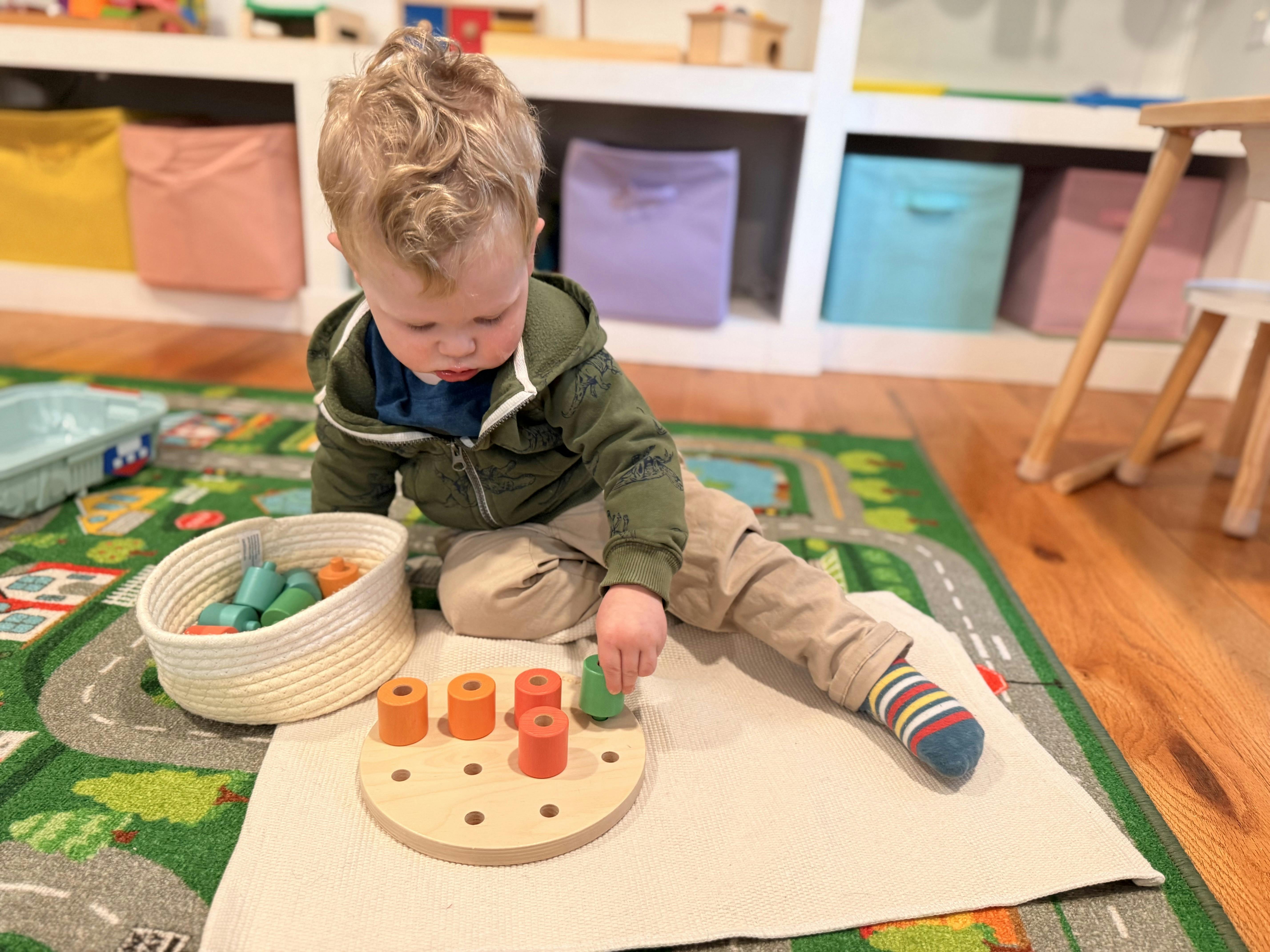 Child playing with a wooden peg toy on a rug