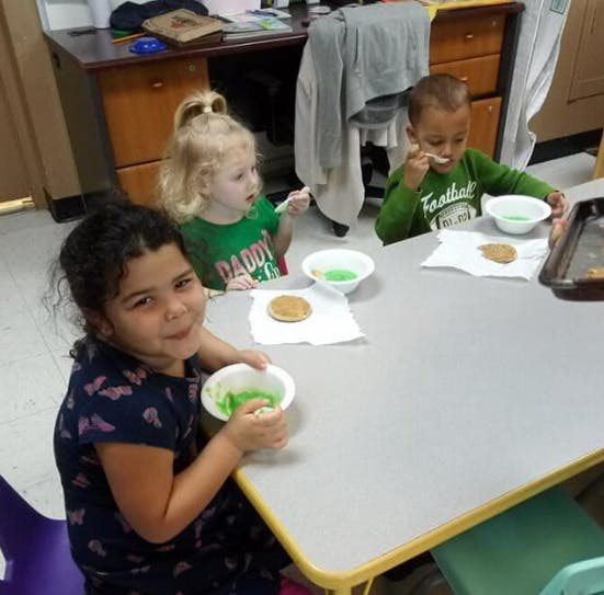 Three children decorating cookies at a table