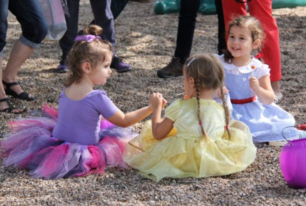 Three children sitting on the ground, two holding hands