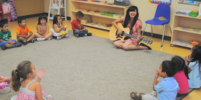 Person playing guitar for children in a classroom