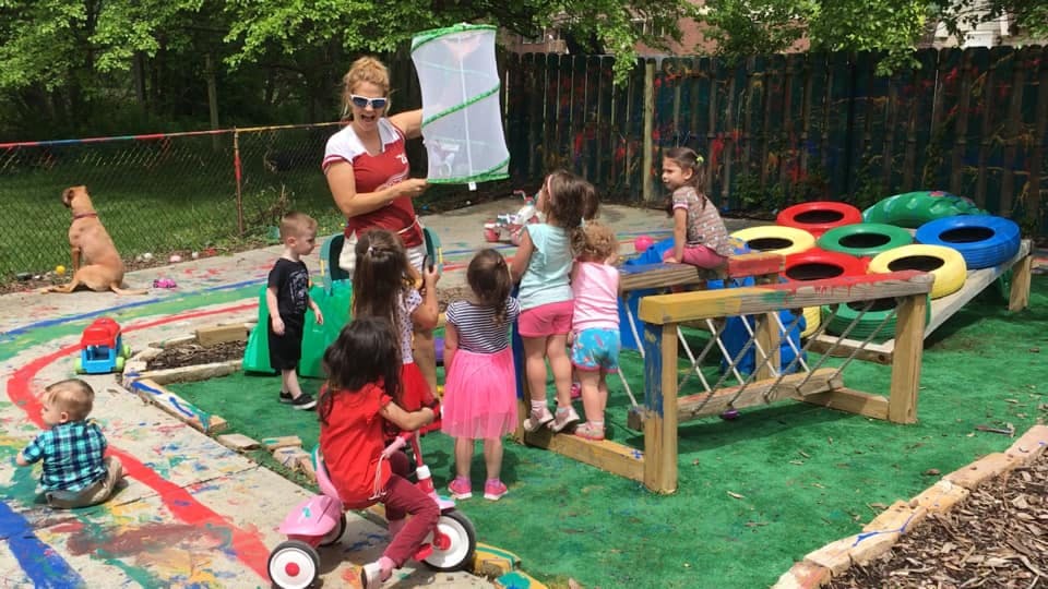 Person showing children a bug net on a playground