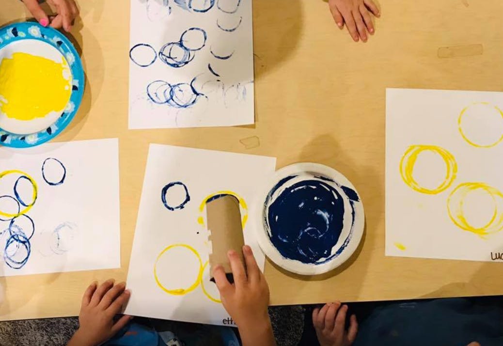 Children making circle prints with paint and cardboard tubes