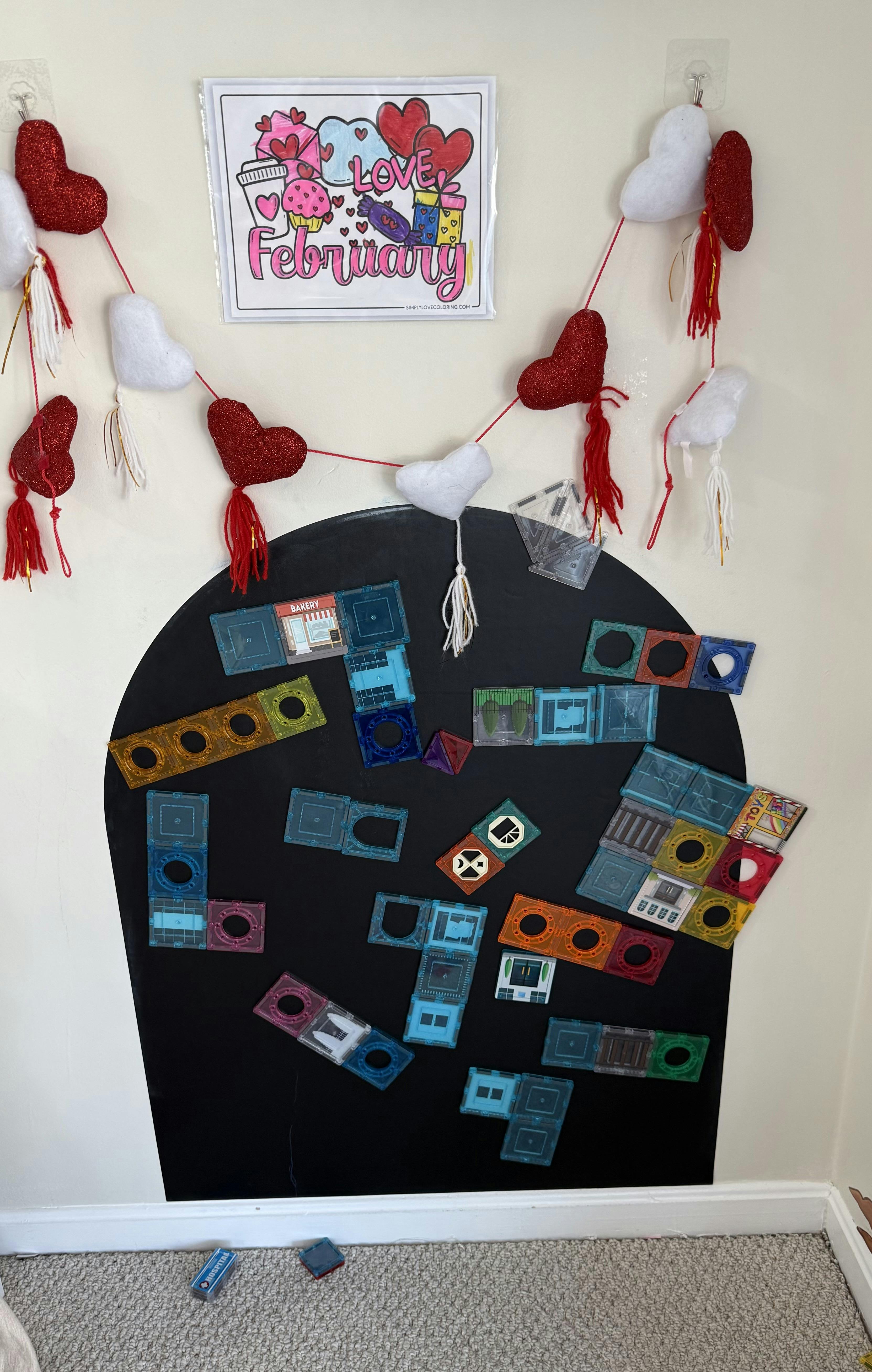 February coloring page and heart garland above magnetic tiles on a wall