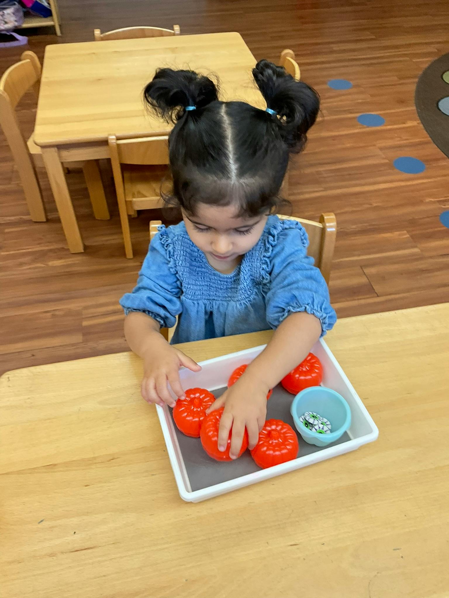 Child playing with red toy vegetables on a tray
