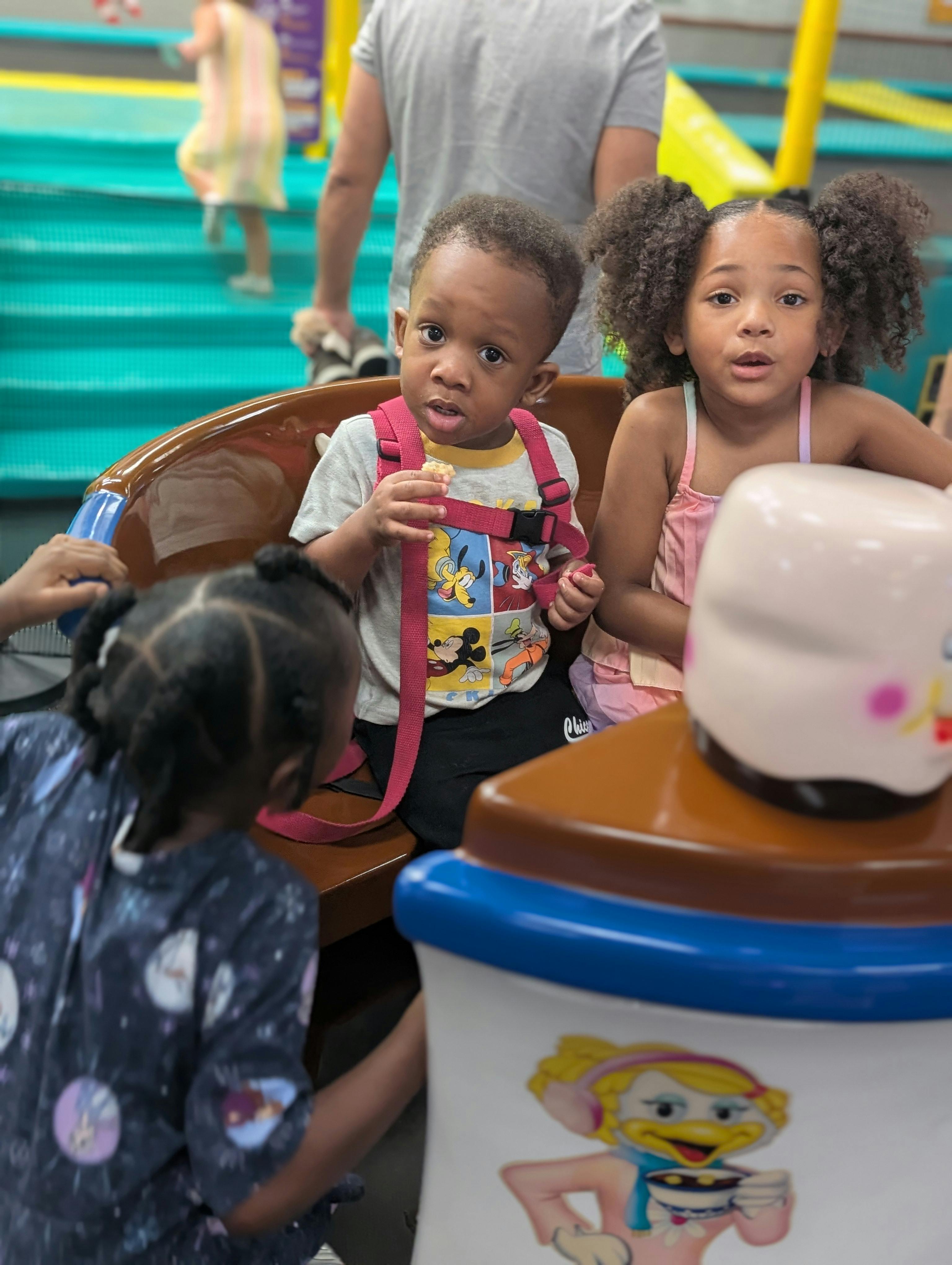 Two children sitting in a booth, one holding food