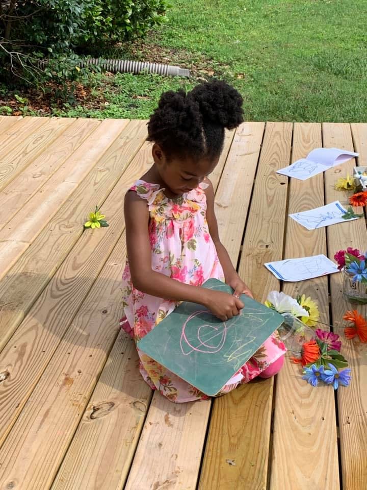 Child drawing on a chalkboard on a wooden deck
