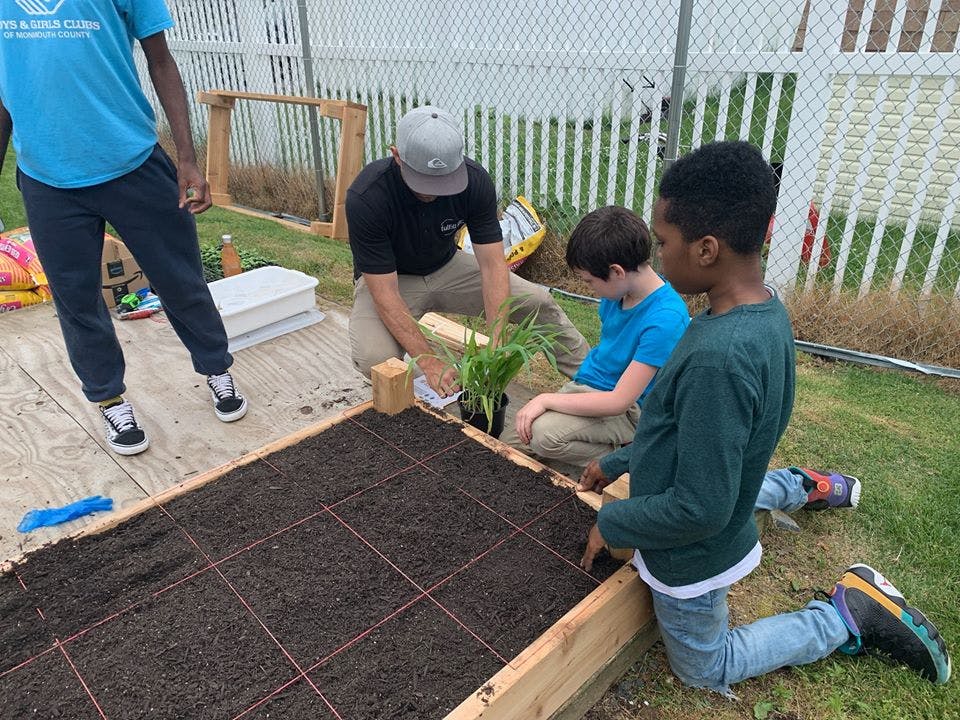 Adult and two children planting in a raised garden bed