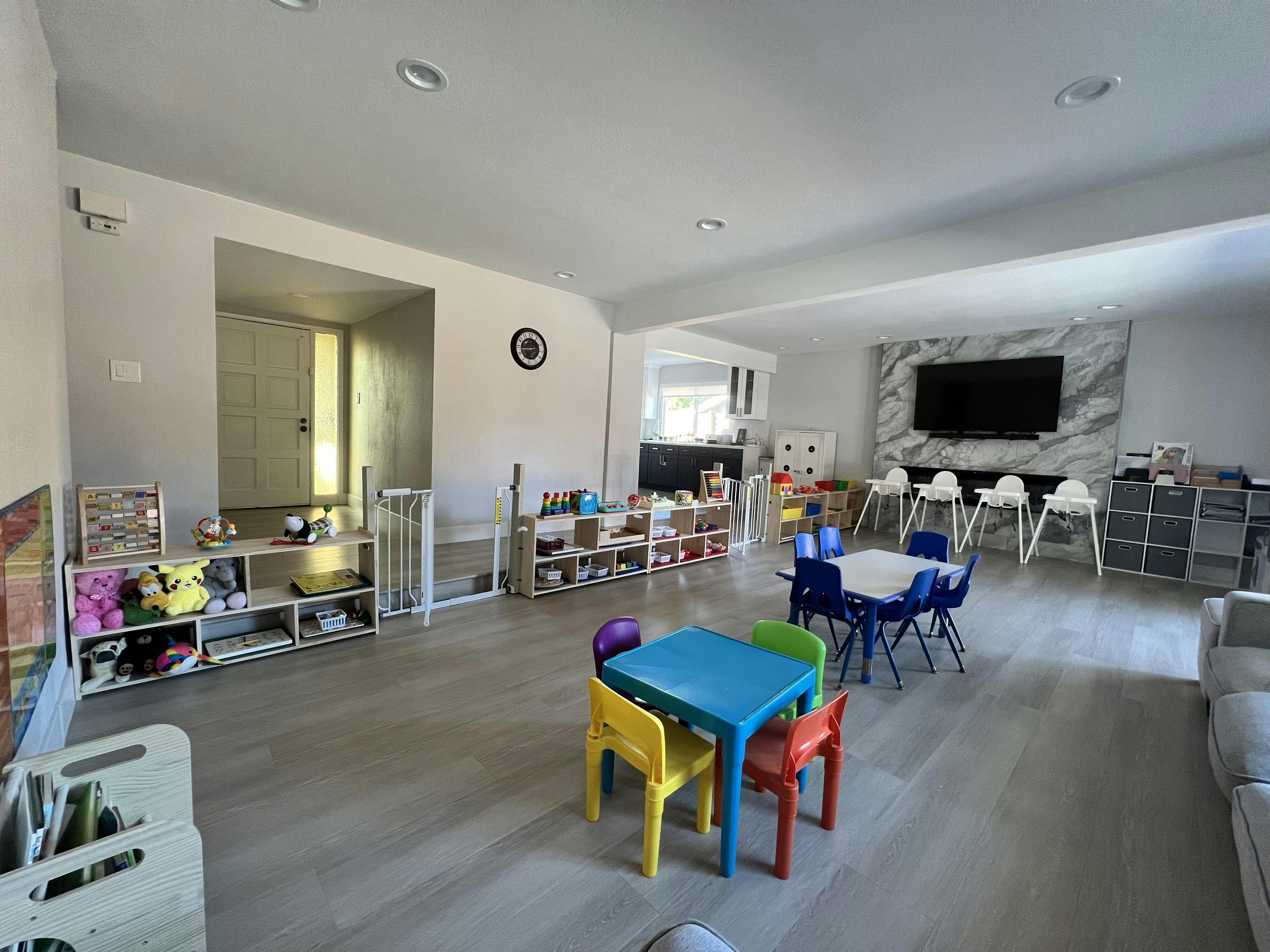 Playroom with small tables, chairs, shelving units, and toys