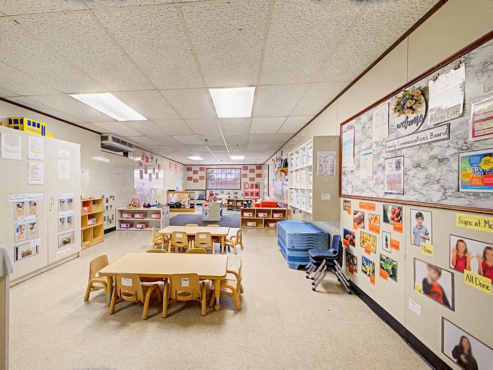 Classroom with small tables, chairs, and bulletin boards