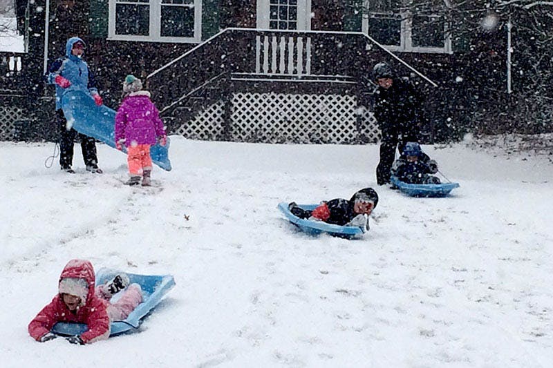 Children playing in the snow with sleds