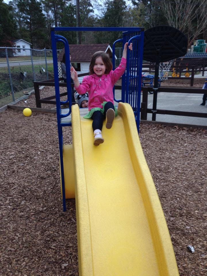 Child on a yellow slide at a playground