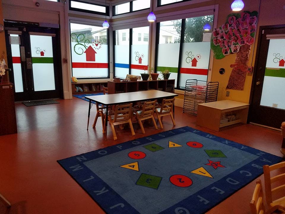 Classroom with a table and chairs, and a blue rug with shapes and letters