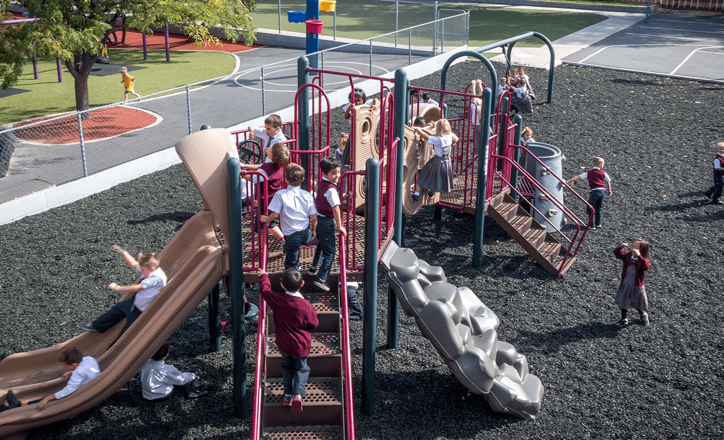 Children playing on a playground structure with slides and climbing structures