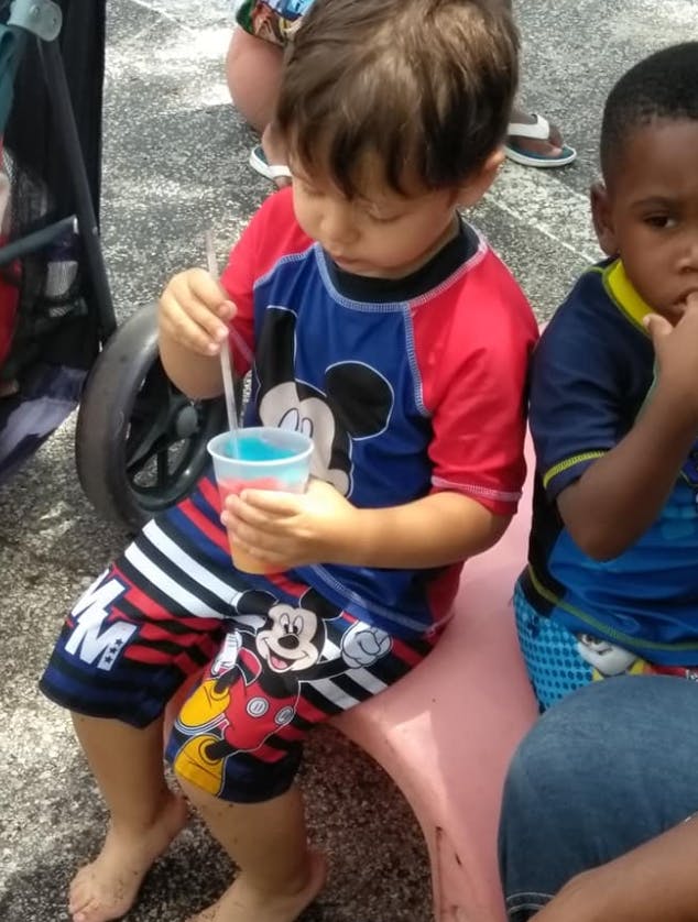 Child in Mickey Mouse outfit holding a cup with a straw