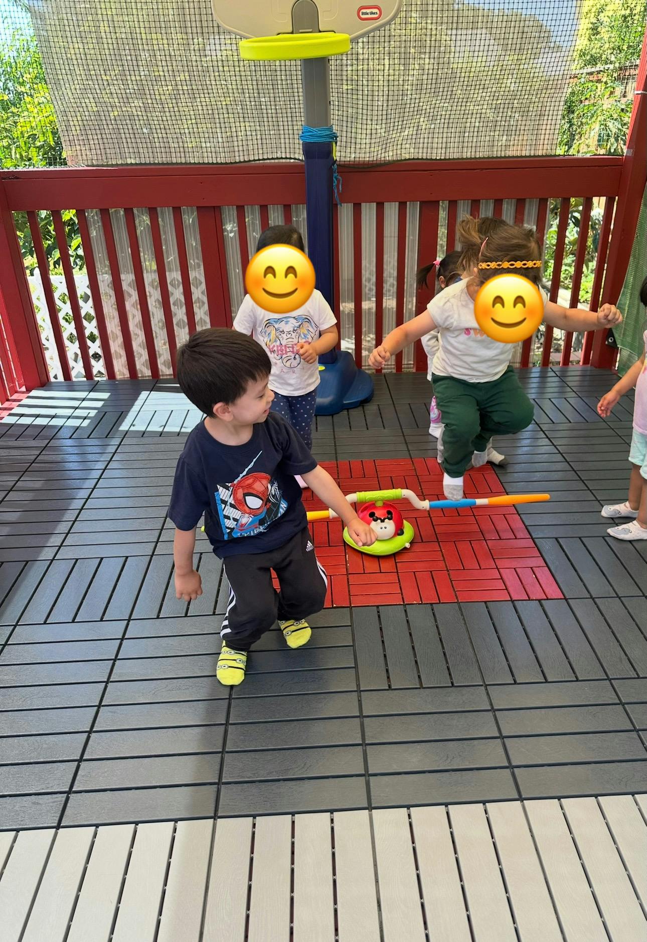 Children playing with a red and green toy on a tiled surface