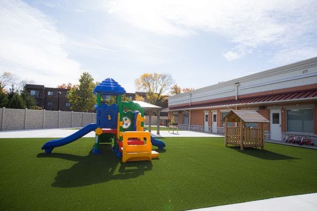 Playground with colorful play structure and small wooden house on artificial turf