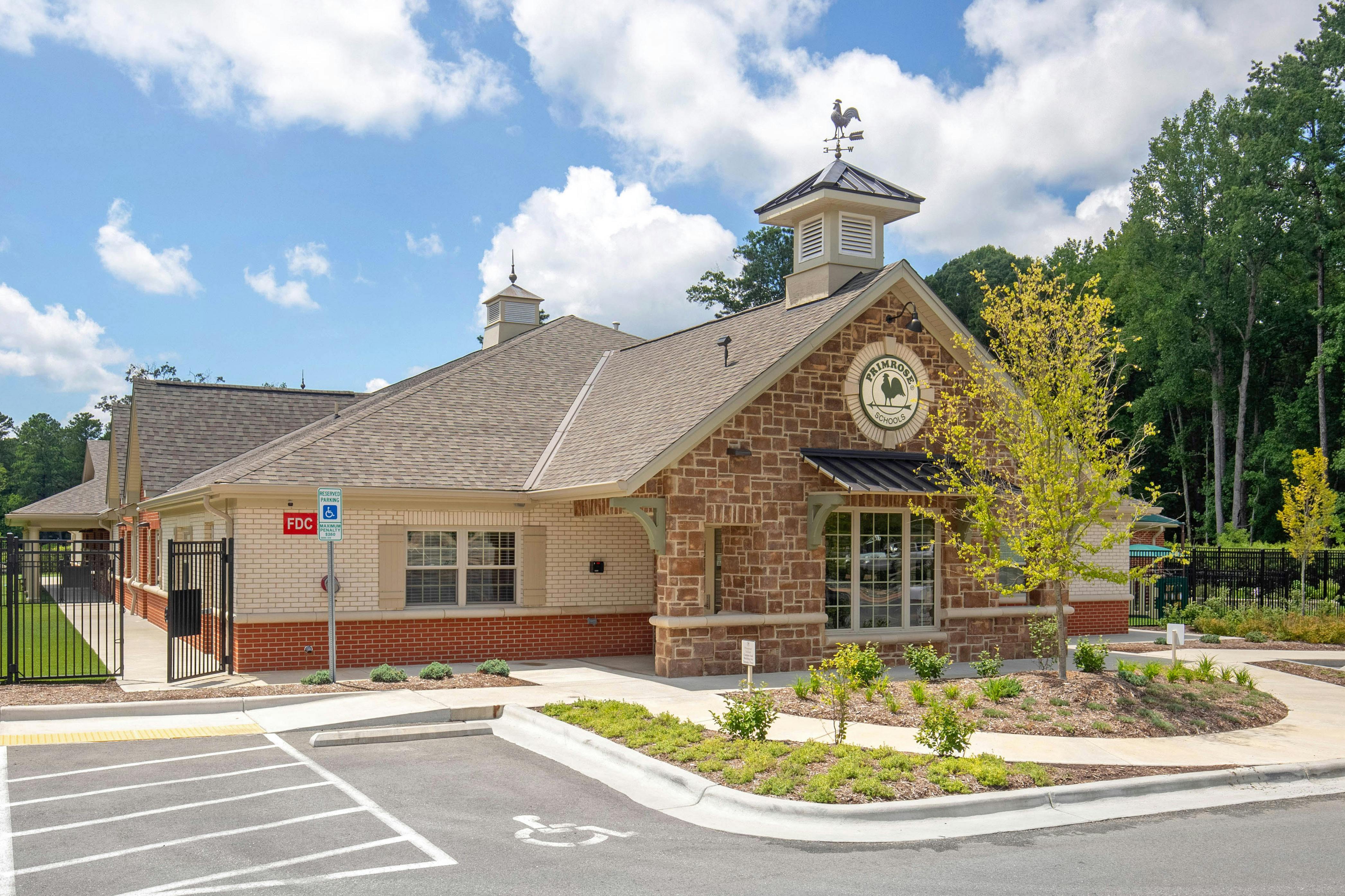 A brick and stone building with a weather vane on the roof and a "Primrose Schools" sign