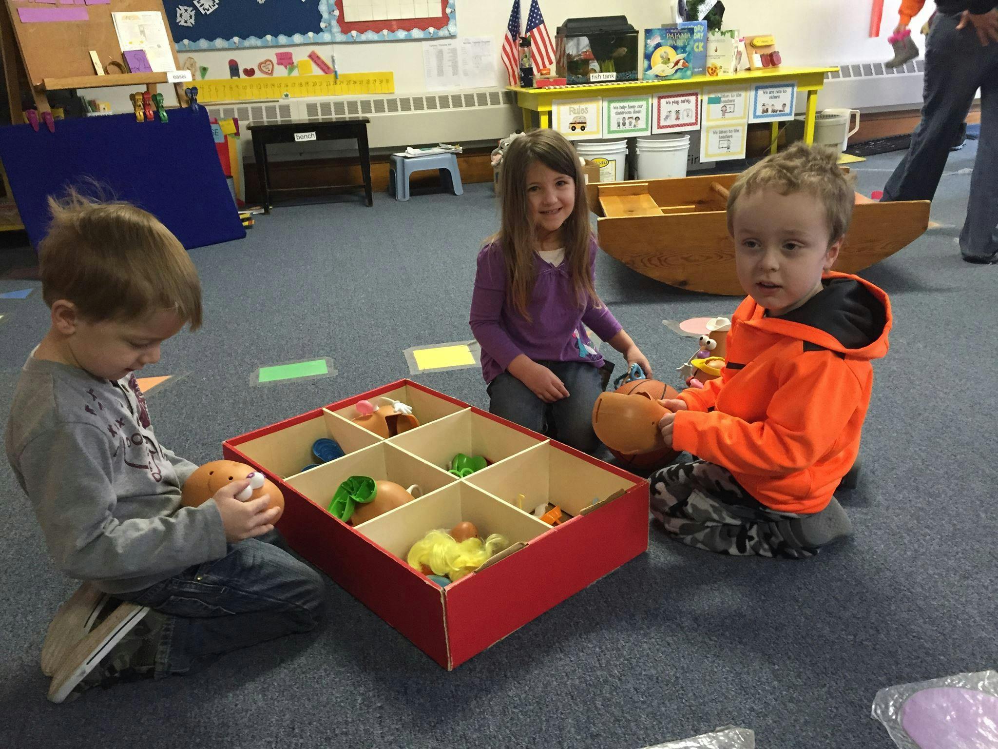 Three children playing with toys in a classroom