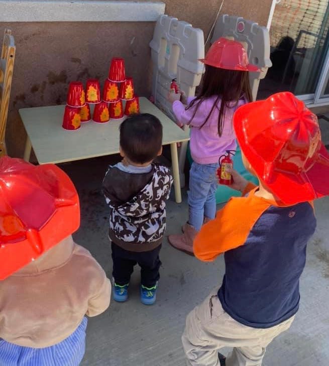 Children playing with toy fire extinguishers and red cups