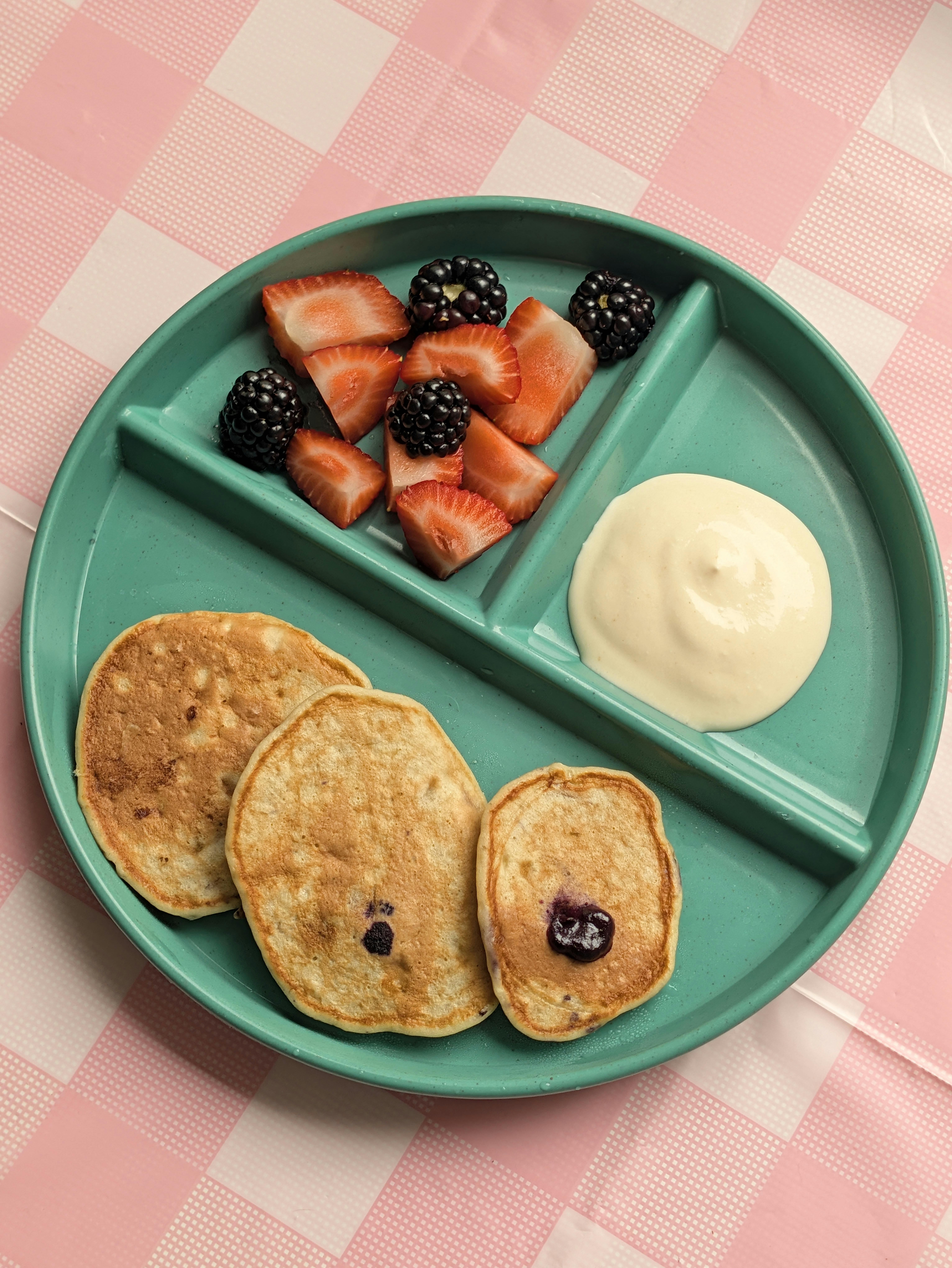 Pancakes with berries and a side of yogurt on a divided tray