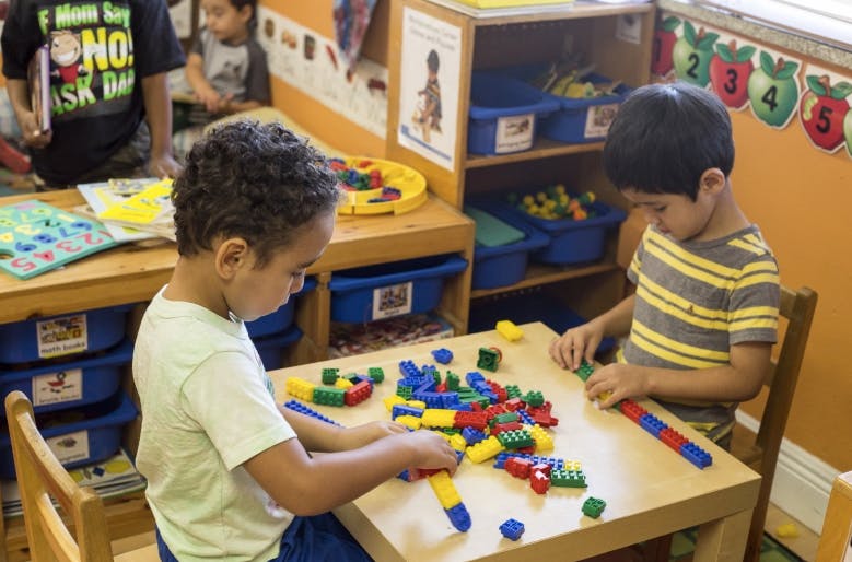 Two children playing with colorful building blocks at a table