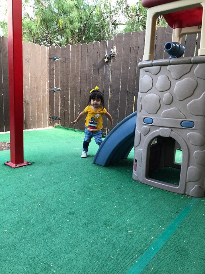 Child standing on green turf next to a play structure