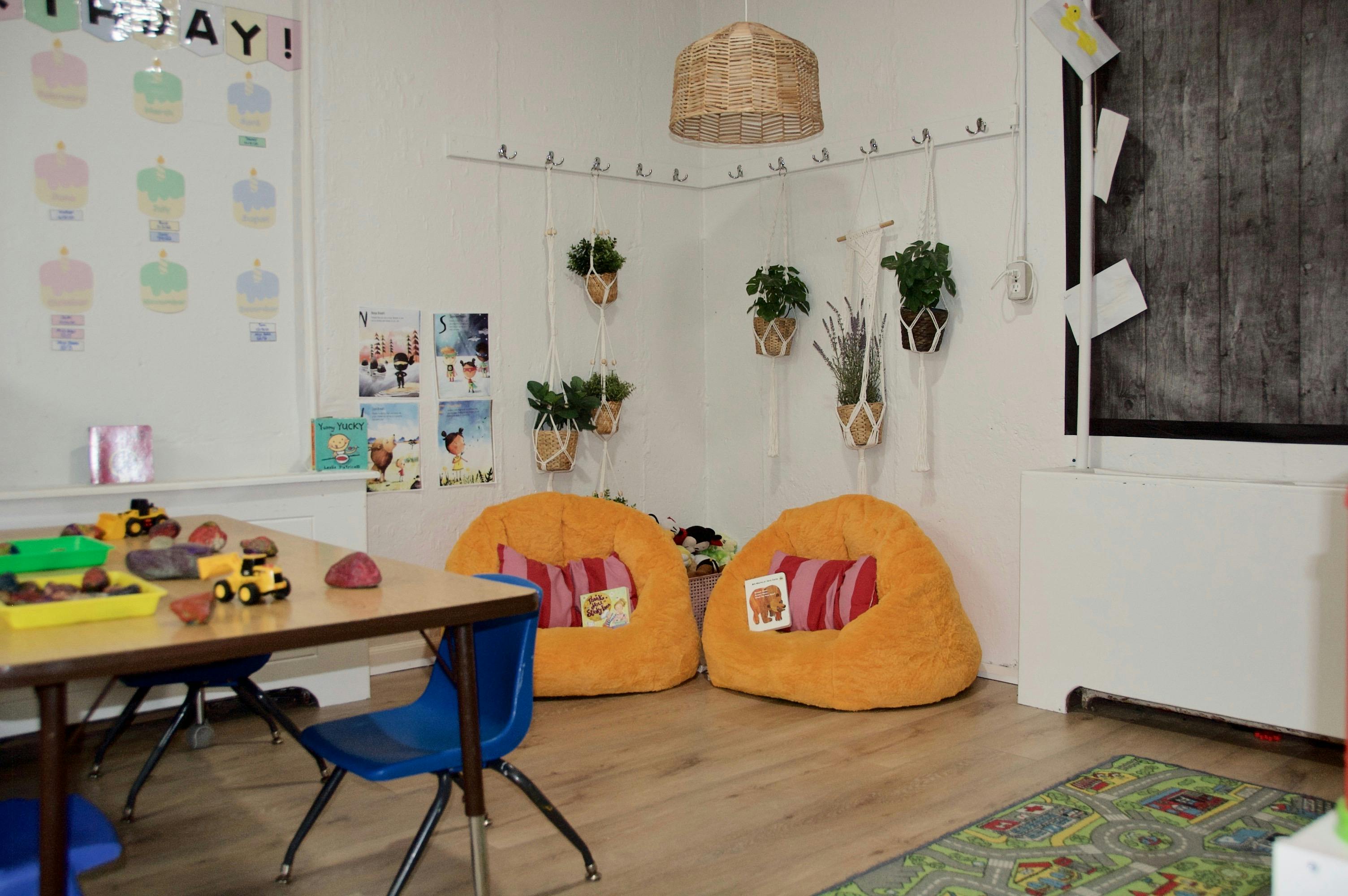 Classroom corner with two orange beanbag chairs and hanging plants