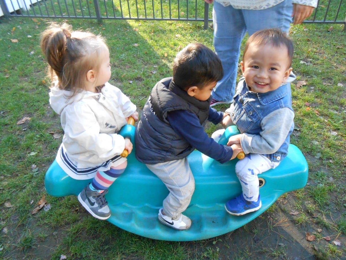 Three children on a playground seesaw