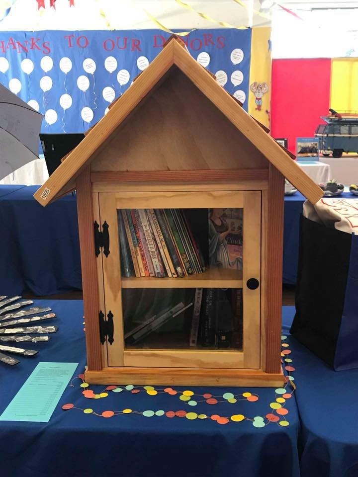 Small wooden house-shaped bookshelf with books inside