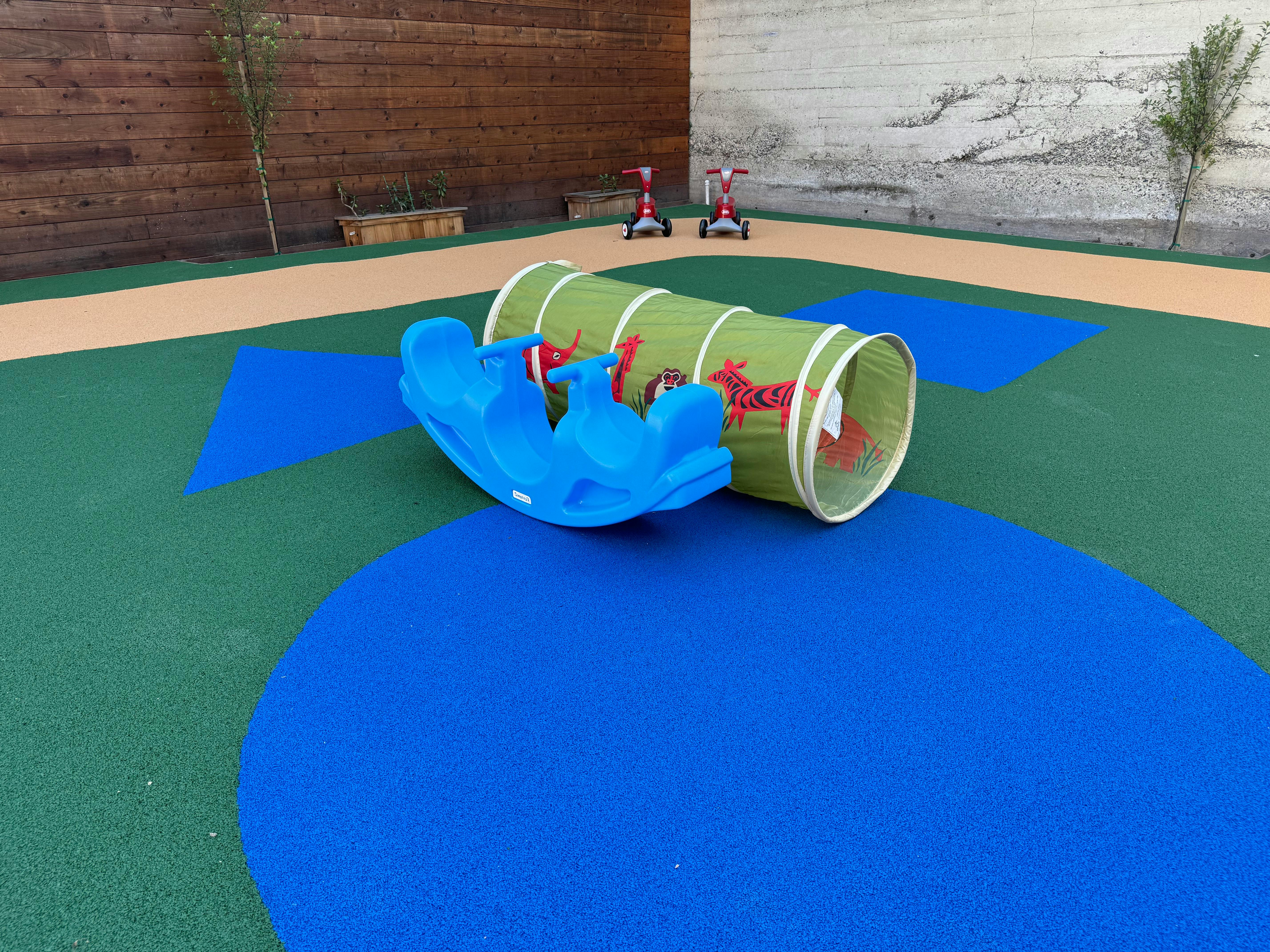 Blue plastic seesaw and green play tunnel on a playground