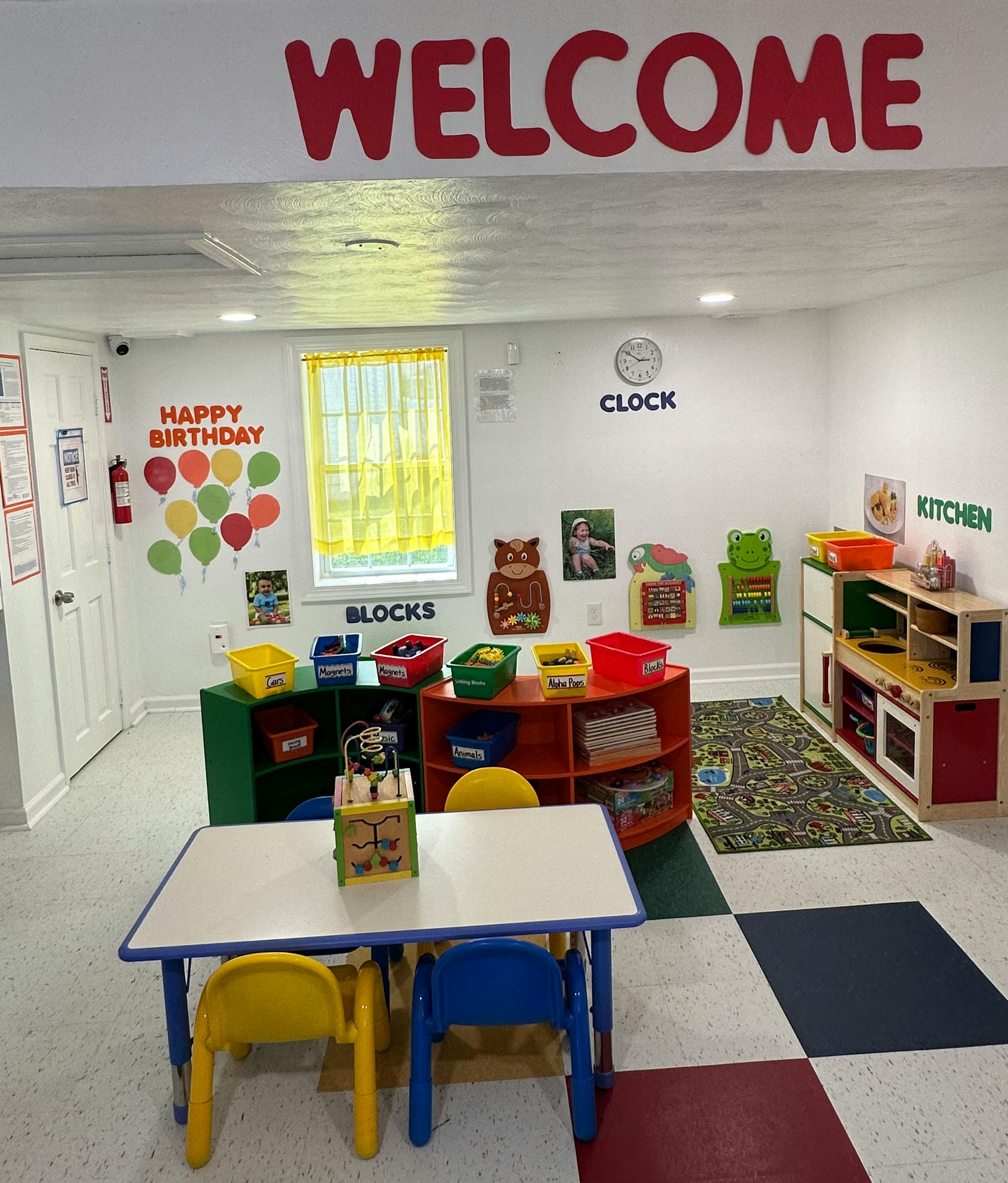 Classroom with small tables and chairs, play kitchen, and storage shelves