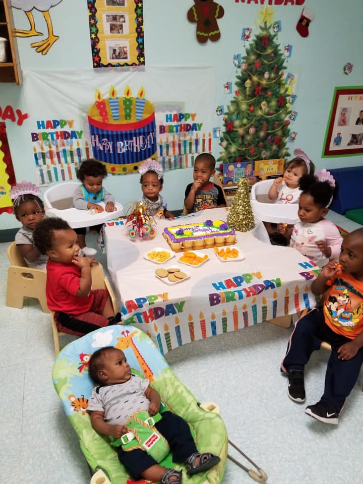Children sitting around a table with a birthday cake and treats