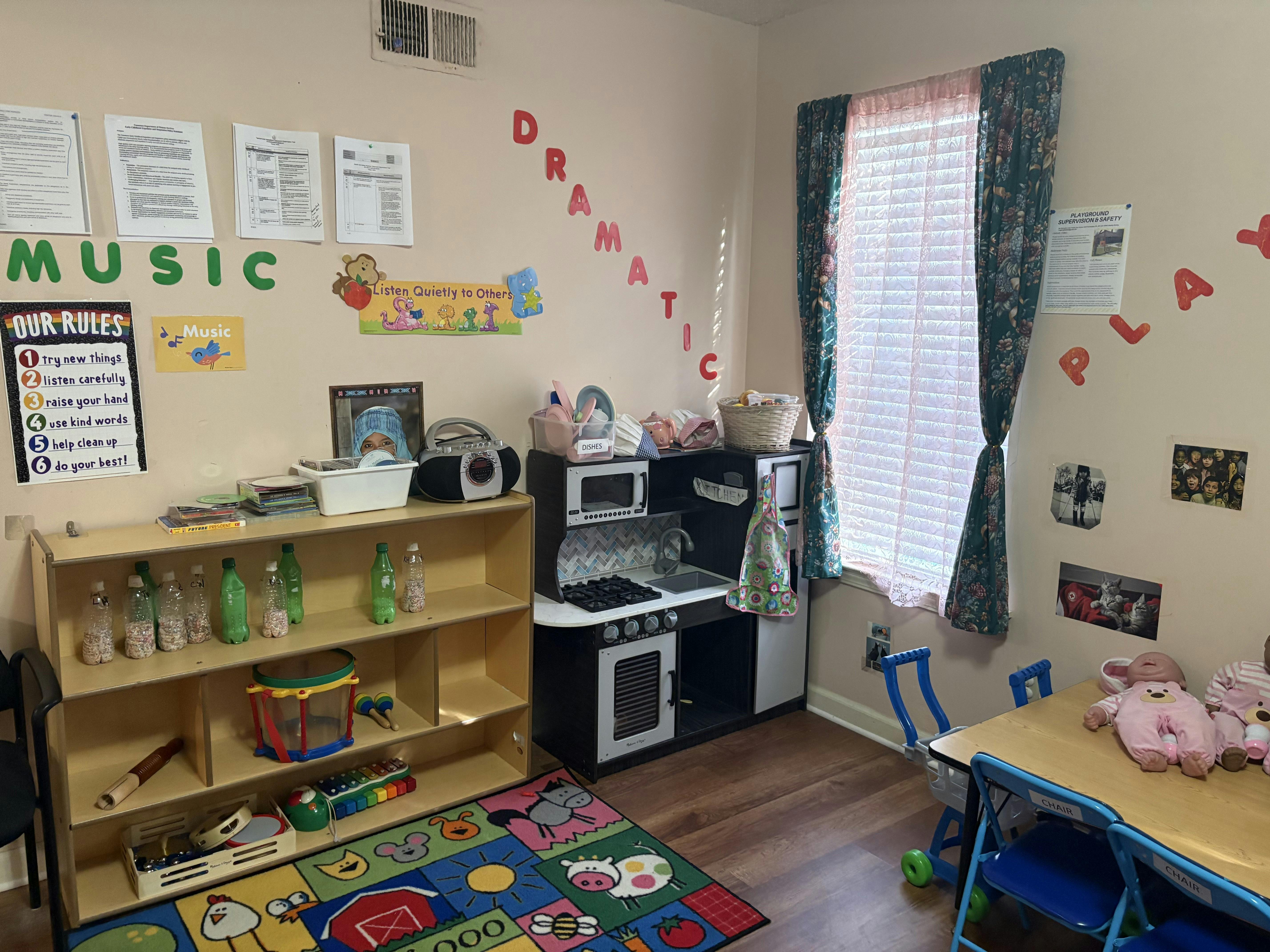 Children's classroom with a play kitchen, toy instruments, and wall decorations