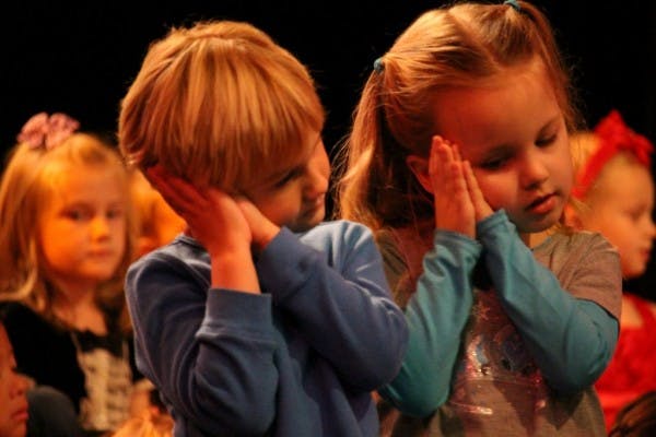 Two children with hands together under their faces