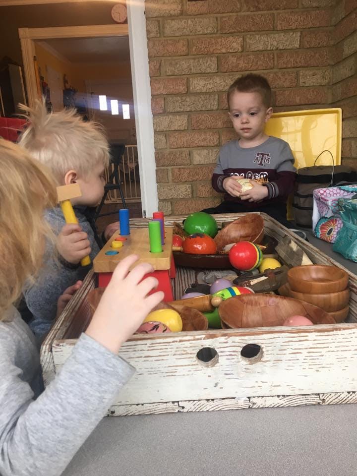 Two children playing with toys in a wooden box