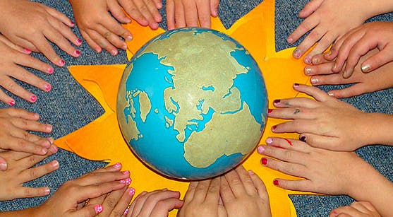 Multiple hands surrounding a globe on a yellow star shape