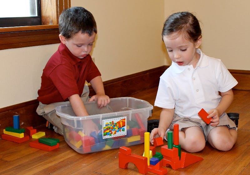 Two children playing with building blocks on the floor