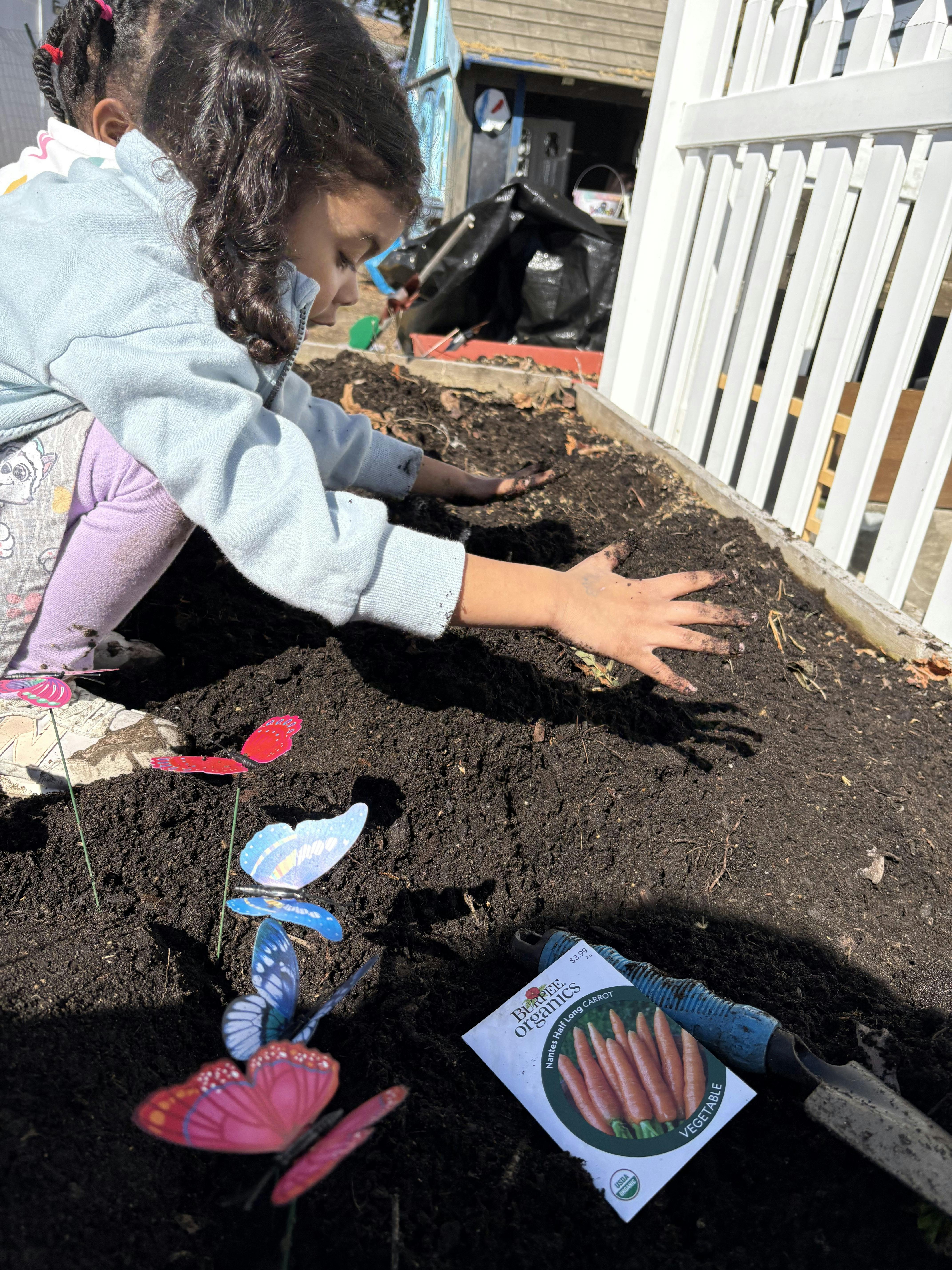 Child gardening, hands in dirt in a raised garden bed